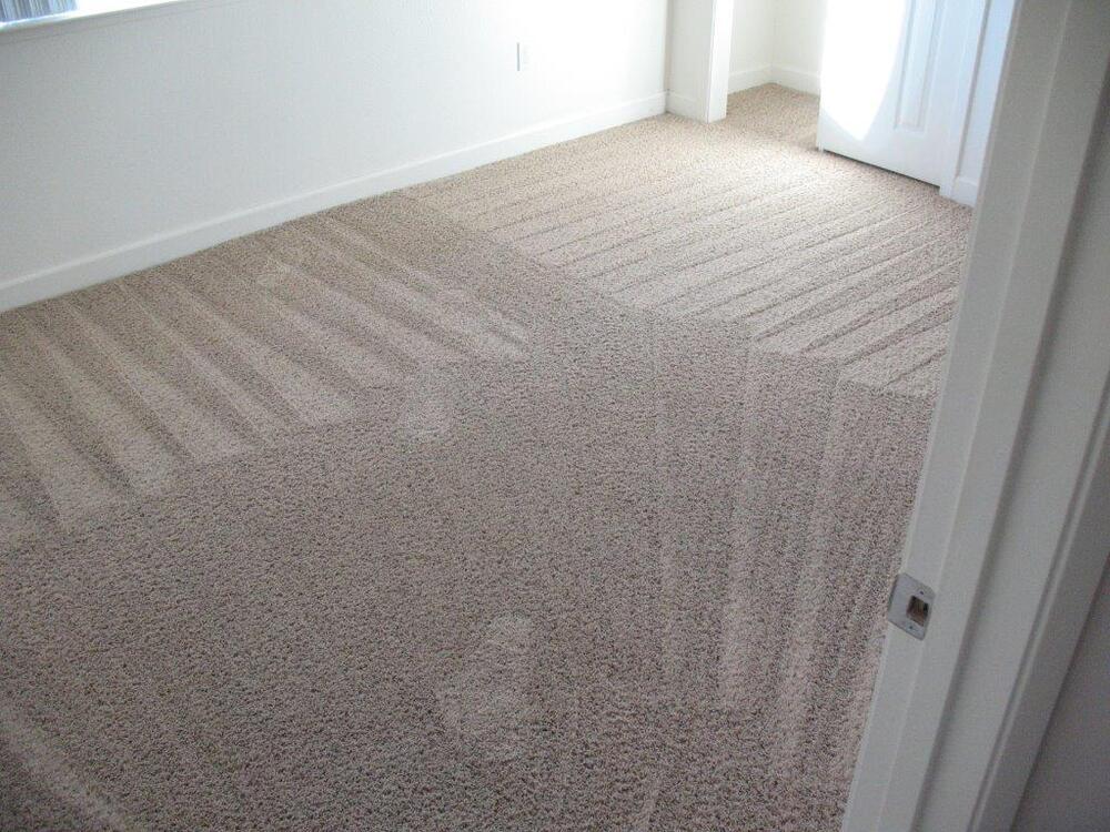 A clean empty bedroom with vacuum marks left from cleaning in the carpet.