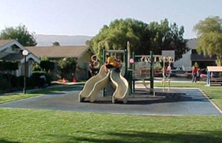 A kids playground with slides and monkey bars sits in the middle of a courtyard.