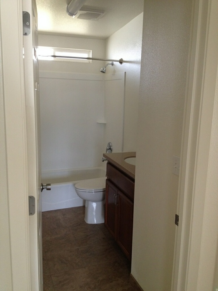 A clean empty bathroom with a shower tub combination, a toilet and sink.