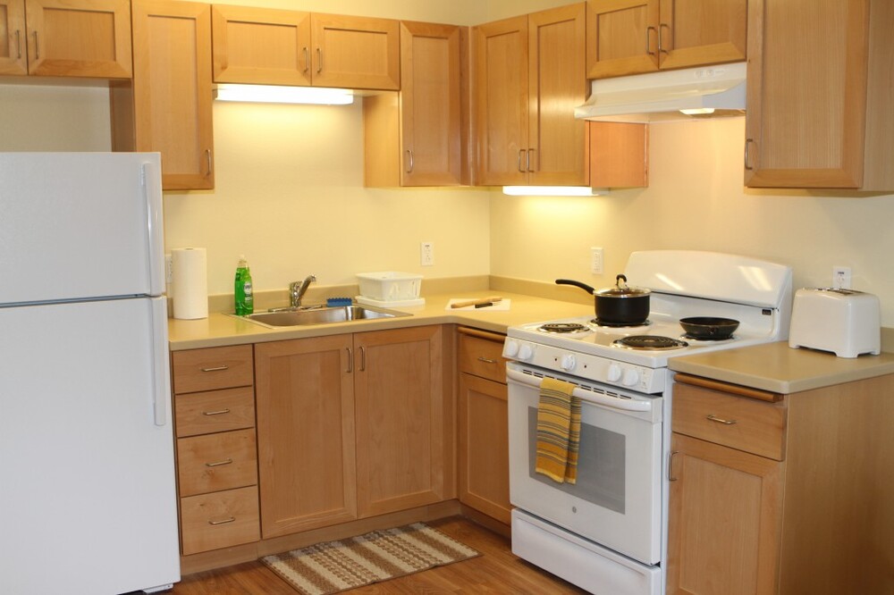 A clean kitchen with wooden cabinets and drawers. 