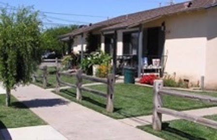 Smooth, clean sidewalks lead up to Guadalupe Senior Housing which sits behind a wooden fence.