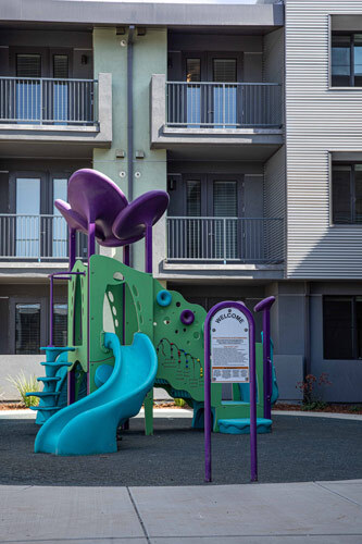 A piece of playground equipment with slides sits in front of The Residences at Depot Street.